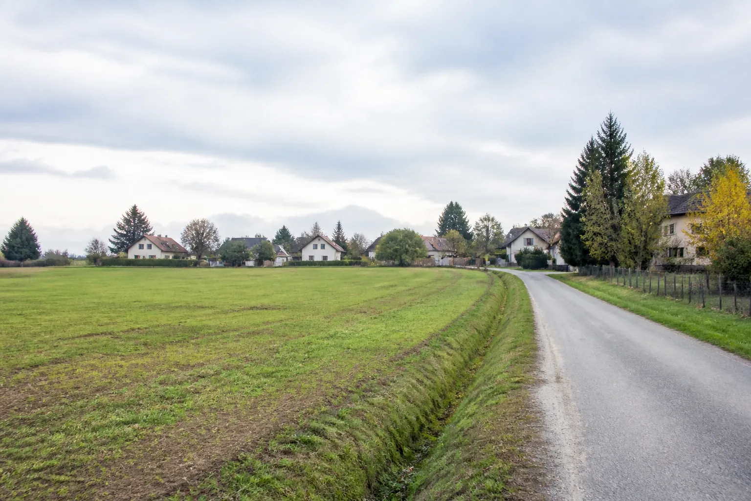 Bestehende Straße entlang einer offenen Fläche am Rand einer österreichischen Siedlung